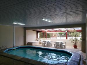a swimming pool in a house with a table and chairs at Hotel Pousada das Flores in Gramado