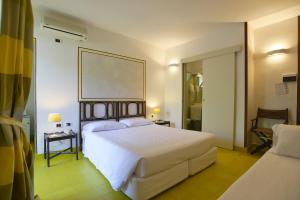 a bedroom with a large white bed and a mirror at UNAHOTELS Club Hotel Ancora in Stintino