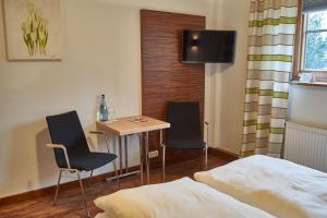 a room with a bed, chair, desk and television at Ringhotel Forellenhof in Walsrode