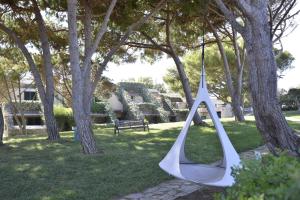 a hammock hanging from trees in a park at UNAHOTELS Club Hotel Ancora in Stintino