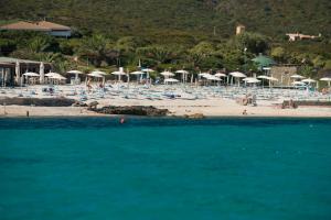a beach with umbrellas and people on the beach at UNAHOTELS Club Hotel Ancora in Stintino