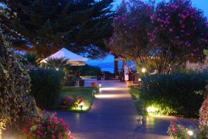 a walkway with flowers and lights in a garden at UNAHOTELS Club Hotel Ancora in Stintino