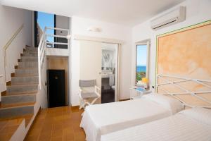 a bedroom with two beds and a staircase at UNAHOTELS Club Hotel Ancora in Stintino