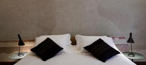 a bed with two black and white pillows and two lamps at Casatorre dei Leoni Dimora Storica in Siena