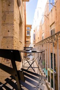 un balcón vacío con mesa y sillas en Charming Valletta 1 bedroom apartment off Republic Street sleeps 4, en La Valeta
