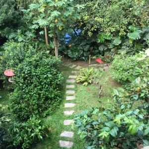 un jardín con un camino de piedra en el césped en CASA RANXOXITA, en Itaipava