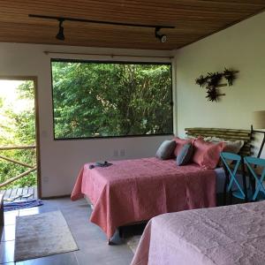 1 dormitorio con 2 camas y ventana grande en CASA RANXOXITA, en Itaipava