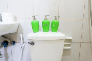- deux conteneurs verts au-dessus des toilettes dans la salle de bains dans l'établissement Alpina Monte Carlo Travellers Inn, à Tagaytay