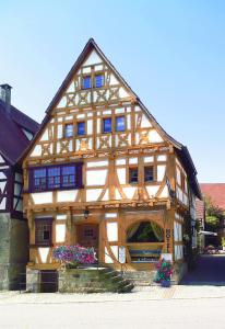 un grand bâtiment en bois avec des fleurs devant lui dans l'établissement Hotel Restaurant Zum Nachtwächter, à Lienzingen