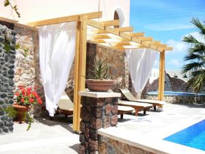 une terrasse avec une pergola et une piscine dans l'établissement Atalos Suites, à Kamari