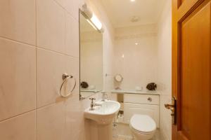 a white bathroom with a toilet and a sink at Beachcombers Apartments in Newquay