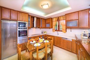 a kitchen with wooden cabinets and a wooden table with chairs at Villa Evelina in Adelianos Kampos +32 photos