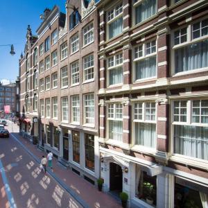 Ein paar Leute laufen eine Straße vor einem Gebäude entlang. in der Unterkunft Hotel Residence Le Coin in Amsterdam