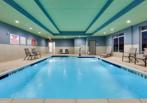 una piscina en una habitación de hotel con sillas y mesas en Holiday Inn Express & Suites - Plano - The Colony, an IHG Hotel, en The Colony