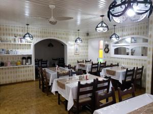 un comedor con mesas blancas, sillas y luces en Hotel Pousada das Flores, en Gramado