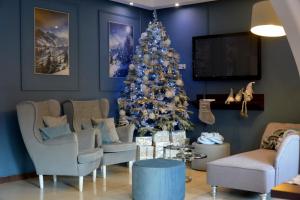 a christmas tree in a living room with chairs and a couch at Willa Florynka in Biały Dunajec