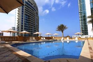 a swimming pool with chairs and umbrellas and a building at HiGuests - Unique Duplex Penthouse in JBR with Sea Views in Dubai