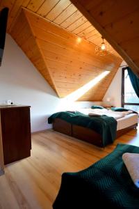 two beds in a room with a wooden ceiling at Willa Florynka in Biały Dunajec