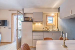 a kitchen with white cabinets and a table with chairs at Appartement Hibou - Welkeys in Megève