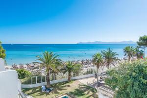 a view of a beach with palm trees and the ocean at Aparthotel Ses Fotges in Playa de Muro