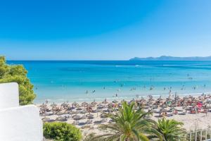 a beach with umbrellas and people in the water at Aparthotel Ses Fotges in Playa de Muro