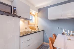 a kitchen with white cabinets and a table at Appartement Hibou - Welkeys in Megève