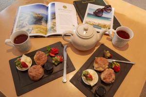 a table with two plates of food and a book at Beachcombers Apartments in Newquay