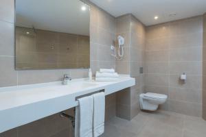 a bathroom with a sink and a toilet and a mirror at Aparthotel Ses Fotges in Playa de Muro