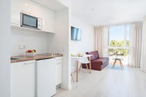 a white kitchen and living room with a couch at Aparthotel Ses Fotges in Playa de Muro