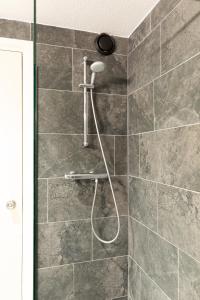 a shower in a bathroom with gray tiles at Bastion Hotel Apeldoorn Het Loo in Apeldoorn