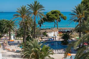 a resort with a pool and palm trees and the ocean at Aparthotel Ses Fotges in Playa de Muro