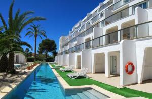 a hotel with a swimming pool next to a building at Aparthotel Ses Fotges in Playa de Muro