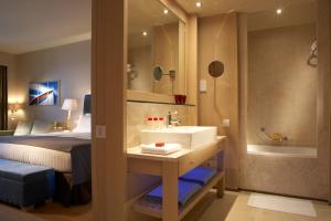 a bathroom with a sink and a bedroom with a bed at Daios Cove in Agios Nikolaos
