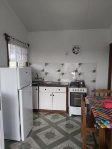 a kitchen with a white refrigerator and a table at Cabañas San Jorge in Termas del Daymán