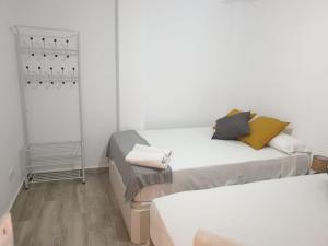 Habitación con 2 camas, paredes blancas y suelo de madera. en Style Apartments Cabanyal Marina Beach, en Valencia