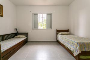 2 camas en una habitación blanca con ventana en Casa em meio a natureza, em frente ao canal, en Florianópolis