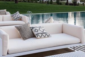 a white couch with pillows sitting next to a pool at Aroeira Lisbon Hotel - Sea & Golf in Aroeira