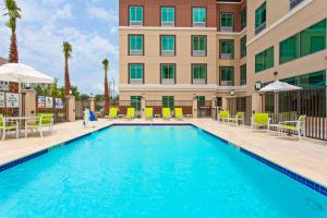 Holiday Inn Express & Suites Houston S - Medical Ctr Area, an IHG Hotel في هيوستن: مسبح امام الفندق فيه كراسي ومظلات