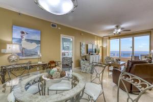 uma sala de estar com uma mesa de vidro e cadeiras em Enclave 1004 em Orange Beach