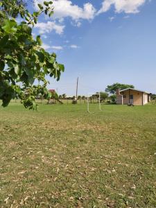 a field of grass with a house in the background at Cabañas San Jorge in Termas del Daymán