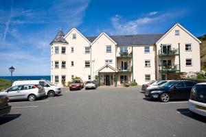 a large white building with cars parked in a parking lot at Beachcombers Apartments in Newquay