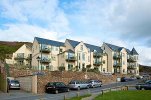 um grande edifício de apartamentos com carros estacionados num parque de estacionamento em Beachcombers Apartments em Newquay