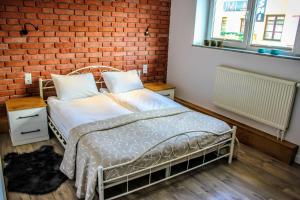 een slaapkamer met een bed en een bakstenen muur bij Main Street Chłodna Apartment in Suwałki