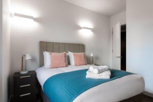 a bedroom with a large bed with towels on it at Abbott House by Viridian Apartments in Saint Albans