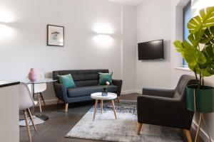 a living room with two couches and a tv at Abbott House by Viridian Apartments in Saint Albans