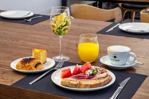 a table with plates of food and a glass of orange juice at One Shot Tabakalera House in Donostia-San Sebastián