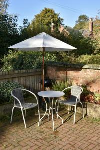 a table and two chairs under an umbrella at Finest Retreats - Shropshire Cottage, 2 bedrooms, sleeps 3 in Marchamley