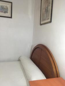 Cama en habitación con cabecero de madera en Pensión Teruel, en Barcelona