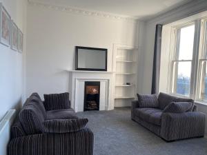 ein Wohnzimmer mit 2 Stühlen und einem Kamin in der Unterkunft Carvetii - Edward House B - 2 Dbl bed 1st floor flat in Dunfermline