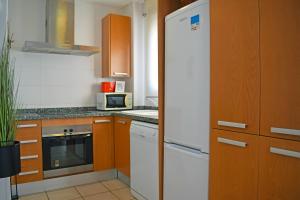 ベルレガートにあるMigjorn Mar de Bellreguard AP9のキッチン(白い冷蔵庫、木製キャビネット付)